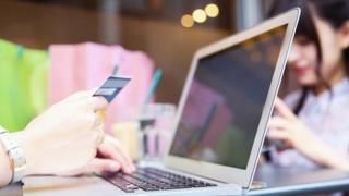 woman holding credit card at laptop