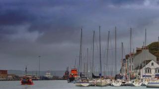 Boats in Weymouth harbour with dark bluey grey skies behind