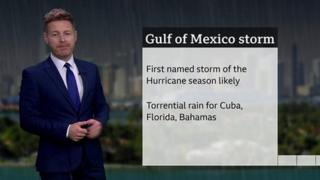 Tomasz Shafernaker standing in front of a slate with details of a developing storm in the Gulf of Mexico
