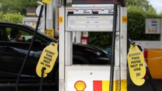 Signs displayed on empty fuel dispensers at a Shell petrol station say 'Sorry this hose is not in use' in Sydney, Australia