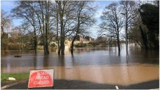 Flooded road with road closure sign at the forefront