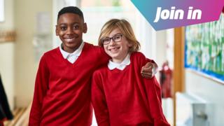Two boys stand in a school corridor. One has their arm around the other's shoulders. They are wearing white polo shirts and red jumpers. "Join in" is superimposed in the top right corner of the image.