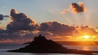 Cloud moving in over the coast with the sun setting in the distance.