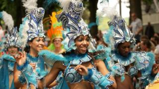 A group of female carnival dancers in blue and silver glittery outfits with scales and fins.