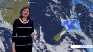 Helen Willetts stands in front of a weather map of New Zealand