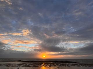 Grey sky over the coast with a setting sun in the distance