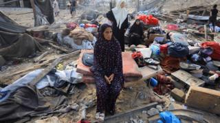 A Palestinian woman sits amidst debris as people inspect the site of an Israeli strike on a house in Gaza City, 30 July 2026.