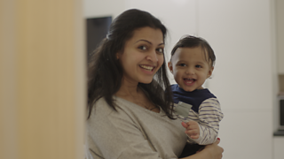 A mum and her son smiling as they look in a mirror