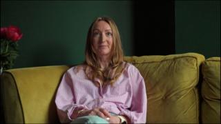 A woman with long blonde hair and a pink shirt sat on a yellow sofa