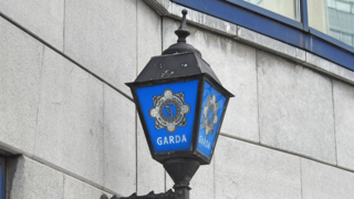 A lantern attached to a building. It shows the gardai's emblem.