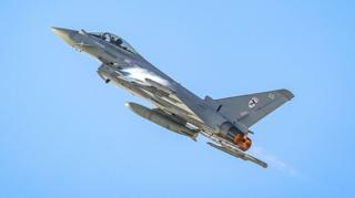 British Royal Air Force Eurofighter Typhoon jet flies upwards into a clear blue sky.