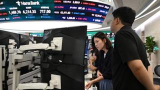 Currency dealers watch monitors as an electronic screen shows South Korea's benchmark stock index (KOSPI) in a foreign exchange dealing room at the Hana Bank headquarters in Seoul on July 28.