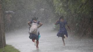 Two school girls dash through torrential rain in Khulna, Bangladesh in August 2022