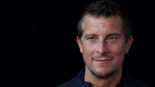 Bear Grylls smiling in front of black background