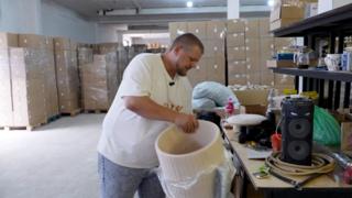 Dmitri unwraps cream-coloured cylinder shaped item of furniture