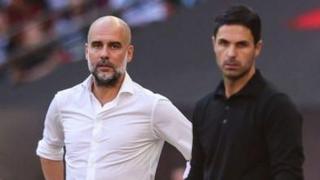 Pep Guardiola, in white shirt, stands alongside Mikel Arteta, who wears a black shirt, as both men look focused