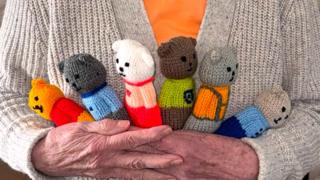 Granny H holding six hand-knitted bears