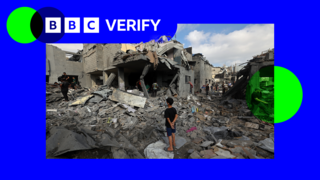 A boy stands amongst rubble following Israeli strikes on Gaza. There is blue and green BBC Verify branding in the top left.