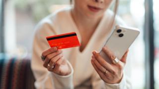 Woman holding red credit card and mobile phone