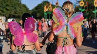 The back view of two women at the festival wearing butterfly wings