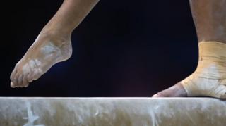 A stock image in a gymnast's feet on the beam