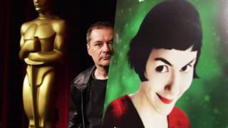 French director Jean-Pierre Jeunet, poses behind a poster for his movie "Amèlie" in Beverly Hills, Los Angeles, 22 March 2002. Jeunet was attending a symposium of directors nominated on this year`s Oscar foreign language list. 