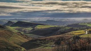 A view over hill tops in Buxton Derbyshire with a cloudy sky in the background