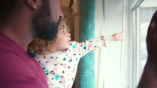 A dad and his daughter looking out of a window