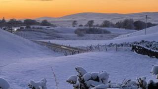 Snow covered fields with an orange sky in the background