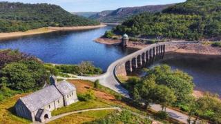 An aerial shot of Rhayader, Powys, showing the bridge crossing the river and mountains in the background.