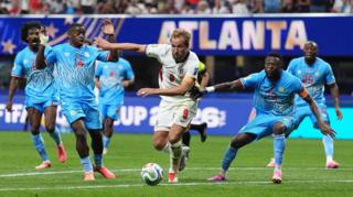 Harry Kane runs towards a ball with DR Congo players chasing him