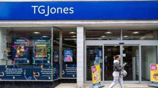 A woman walks in front of a TG Jones store front.
