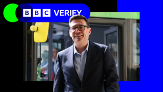 Andy Burnham standing by a bus