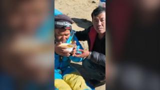 Survivor holding soup bowl next to another man