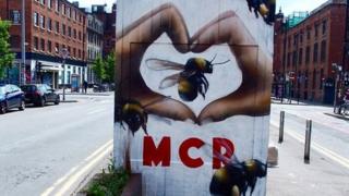 Graffiti showing hands in a heart shape around a bee, and MCR initials