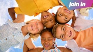 Five children linking arms and looking down into the camera.