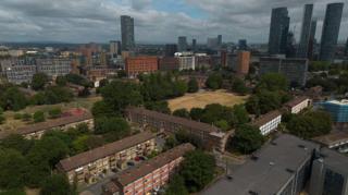 An aerial photograph taken with a drone shows high-rise towers behind social housing blocks in Manchester.