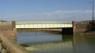A view of Exceat Bridge, taken from a river bank.