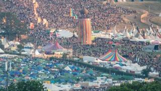 An aerial view of the Glastonbury site with tents and crowds.