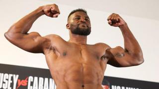 Francis Ngannou flexes and smiles while weighing in