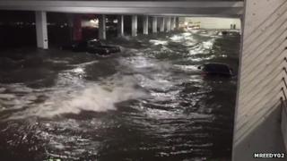 Floodwater streams through an underground car park in Biloxi, Mississippi. Cars are floating in the water.