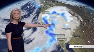 Sarah Keith-Lucas stands in front of a weather map of California showing the latest storm track