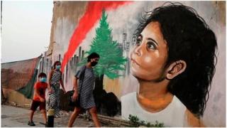 Pedestrians walk past a mural painting depicting a young Lebanese girl who suffered a face injury in the Beirut port blast