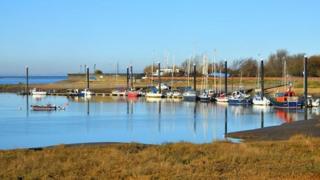 Boats sit in a harbour with blue skies above