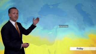 Nick Miller stands in front of a weather map of Turkey and Syria showing cold weather