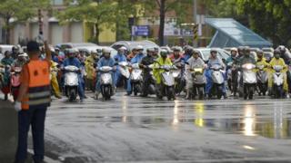 Motorcyclists in rainjackets riding through the effects of storm Haitang