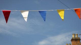 Coloured bunting strung across a nearly cloudless blue sky