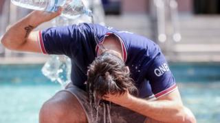 A man pours water over his head to cool down.