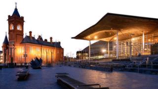 Llun o adeilad y Senedd ac adeilad y Pierhead ym Mae Caerdydd yn erbyn cefndir gwyn.