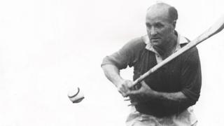 A black and white image of a man hurling.